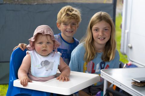 Tre barn koser seg på camping